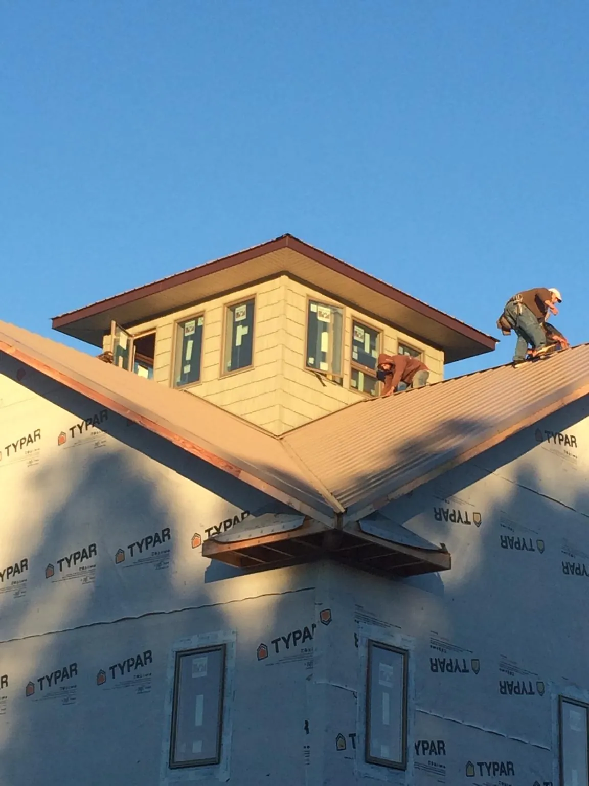Roofers working around a rooftop cupola on a new metal roof at sunset — Roof Waterproofing in Abrams by Roofing Brothers